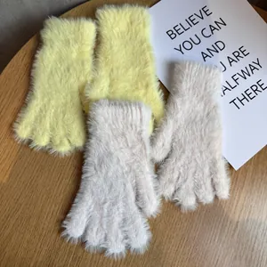Gants tactiles en peluche jaune et rose sur un fond de bureau en bois rustique