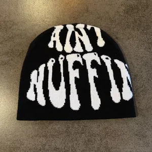 Macro detail of high-quality black knit beanie with white jacquard lettering design