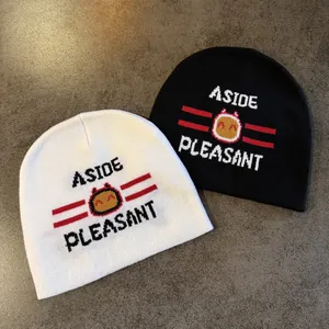 Close-up of knitted beanies featuring ASIDE PLEASANT text and yellow cartoon face