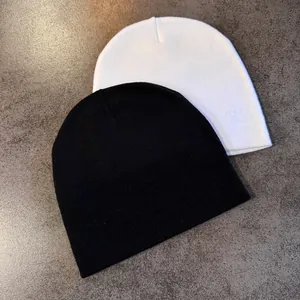Close-up detail of knitted beanies in black and white colors on a grey stone background