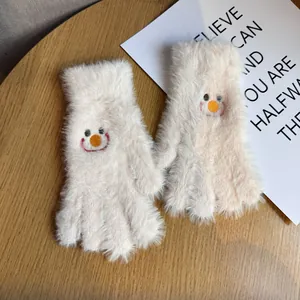 Détail de gants en peluche beige avec broderie de visage souriant et texture chaude