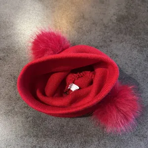 Detalle del gorro rojo de punto con pompones rosas y etiqueta de cuidado en el interior