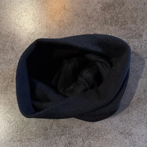Detail view of the fine knitting process and stitching on a black winter beanie hat