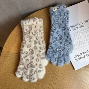 Detailaufnahme flauschiger Plüschhandschuhe mit Leopardenmuster in Beige und Blau