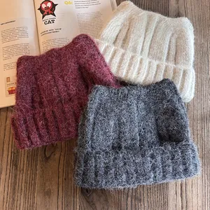 Berretti in maglia con orecchie di gatto in bordeaux, panna e grigio su legno