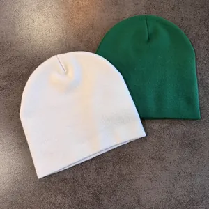 Texture détaillée du tricot des bonnets blanc et vert foncé sur une surface texturée