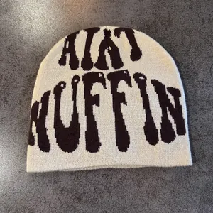 Detailed knit texture of a cream beanie featuring dark jacquard AINT NUFFIN lettering