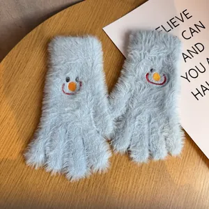 Gros plan de gants en peluche bleu clair avec un smiley brodé et une texture douce et chaude