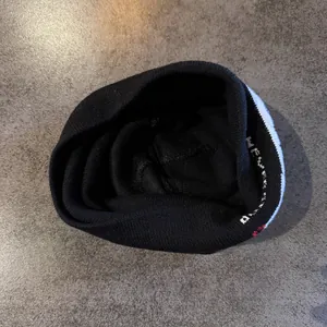 Détail macro du bonnet en maille noire et du motif tissé rouge et blanc sur tissu doux