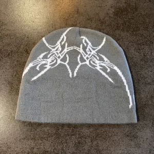 Gros plan du bonnet en maille gris foncé avec motifs de toile d'araignée jacquard blanc