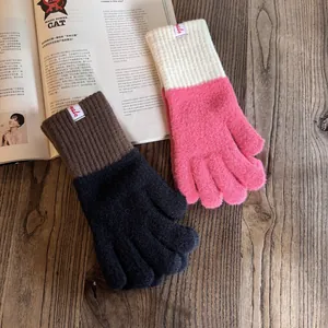 Detail von farbblockierten Strickhandschuhen in Rosa und Braun auf Holzuntergrund