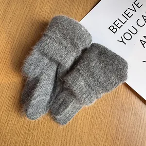 Close-up of grey knit gloves with fluffy mohair cuffs on a wooden background