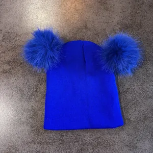 Detalle del tejido de punto acanalado en un gorro azul brillante con dos pompones suaves
