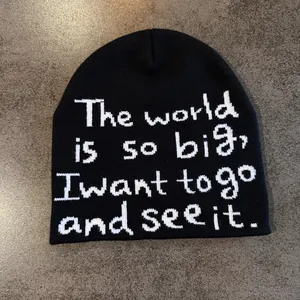 Gros plan d'un bonnet en maille noir avec texte jacquard blanc sur fond gris plat