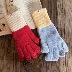 Detail von Strickhandschuhen mit farblich abgesetzten Rippbündchen auf Holzgrund