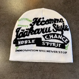 Détail du bonnet blanc montrant le texte jacquard noir et vert et la texture tricotée