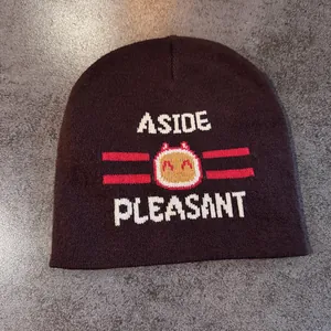Detailed knit of dark brown beanie with cartoon jacquard pattern and white letters