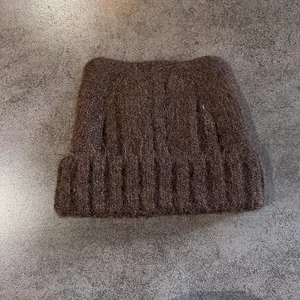 Dettaglio del berretto in maglia marrone scuro con orecchie da gatto e soffice mohair