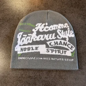 Détail de la texture en tricot du bonnet gris avec lettrage jacquard blanc et vert
