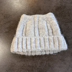 Dettaglio del berretto con orecchie di gatto in maglia grigia con texture in mohair