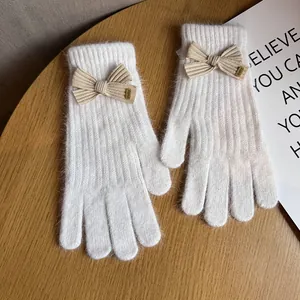 Close-up of plush cream-colored knit gloves with a khaki bow and Baby label detail