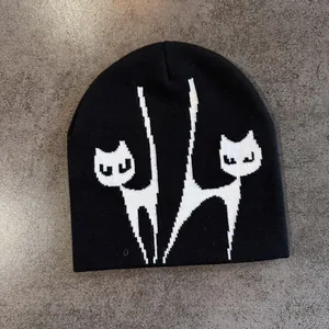 Detailansicht der weichen Stricktextur und des weißen Katzen-Jacquardmusters auf der Mütze