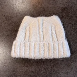 Dettaglio del berretto in maglia bianco crema con orecchie da gatto e trama morbida