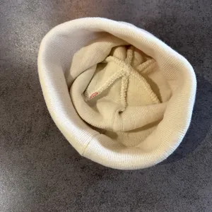 Detailoverzicht van de stiksels en ribgebreide textuur in de beige gebreide muts