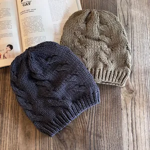 Berretti in maglia a trecce grigio scuro e kaki su fondo in legno per l'inverno