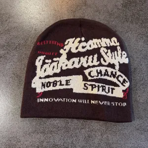 Détail d'un bonnet marron foncé avec lettrage jacquard blanc et rouge style urbain