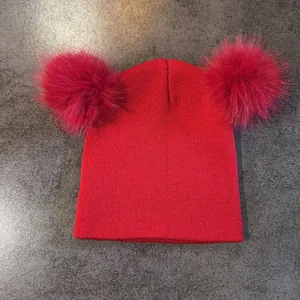 Textura detallada de punto de gorro rojo con pompones dobles de piel sintética rosa