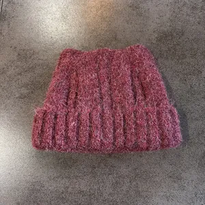 Dettaglio macro del berretto a maglia bordeaux con orecchie di gatto e trama in mohair