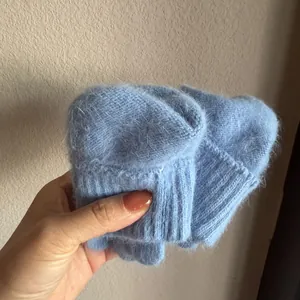 Detail of light blue fluffy rabbit hair knit gloves showing warm fuzzy texture and rib cuff