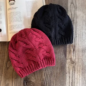 Dettaglio della maglia a trecce su berretti neri e rosa su un tavolo di legno