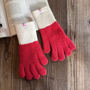 Detail von rot-weißen Strickhandschuhen mit Rippbündchen auf rustikalem Holztisch