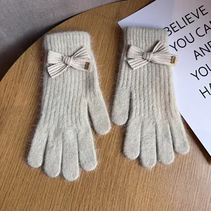 Close-up of beige knitted gloves with cute bow tie decoration and soft fuzzy texture