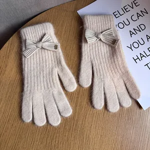 Detail of cream white knit gloves featuring a cute 3D bow and Baby metal tag