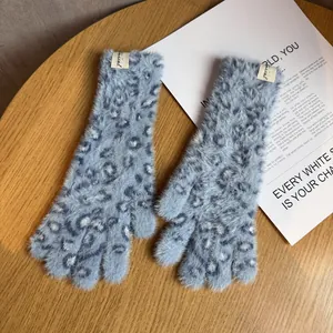 Nahaufnahme hellblauer Plüschhandschuhe mit Leopardenmuster und Special-Webetikett aus Holz
