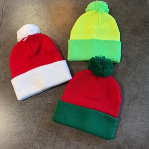Three colorful knitted beanies with pom-poms in festive red and green color schemes