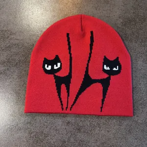 Detail der Strickstruktur einer roten Mütze mit schwarz-weißem Fuchs-Jacquard-Muster