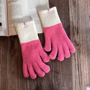 Detail von rosapinken Strickhandschuhen mit cremefarbenen Rippbündchen auf Holztisch