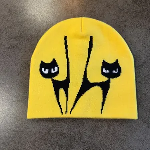 Nahaufnahme der gelben Strickmütze mit schwarzem Katzen-Jacquard und weicher Wolltextur