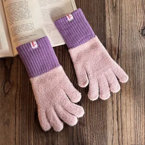Details von Strickhandschuhen mit lila Rippbündchen und plüschigen rosa Handflächen