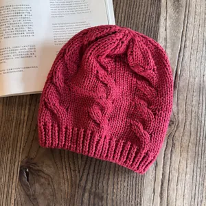 Dettaglio della maglia a treccia spessa di un berretto invernale rosa su legno