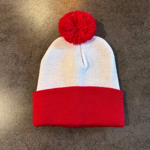 Close-up of red pompom on white knitted beanie with high-quality ribbed texture