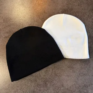 Detail view of black and white knitted beanies showing fine texture and elasticity