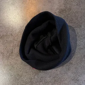 Detailed view of black knitted beanie stitching with thick texture and red accent thread