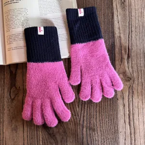Detail eines rosa Strickhandschuhs aus Nerzimitat mit schwarzer Rippmanschette und Etikett