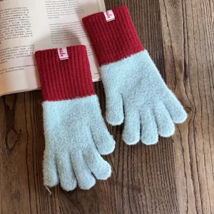 Detail von rot-blau gestrickten Handschuhen mit Plüschstruktur auf Holzgrundlage