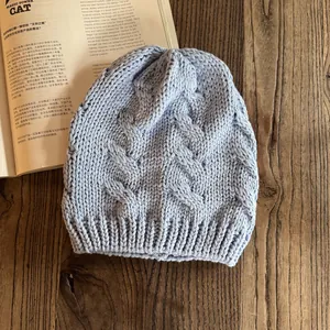 Dettaglio del cappello in maglia a trecce azzurro con trama spessa e risvolto a costine